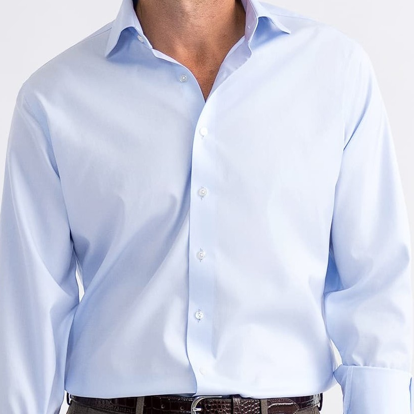Homem vestindo uma elegante camisa social branca confeccionada sob medida da marca Perffeto Alfaiataria. O homem está vestindo também um grava azul escuro.