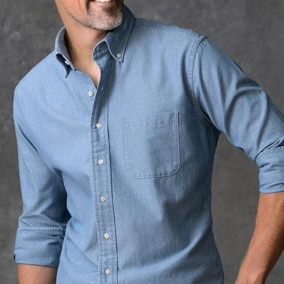 Um homem vestindo um bela camisa azul (lavagem jenas) feita sob medida da marca Perfetto Alfaiataria.